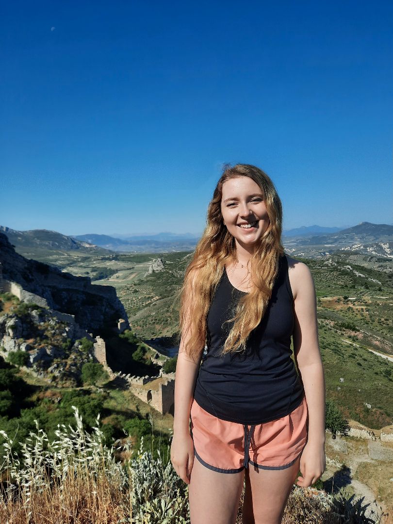 Zoe standing on hill with Grecian landscape behind her