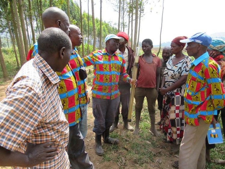 A group of Ugandan conservationists and crane custodians gather in a half circle.