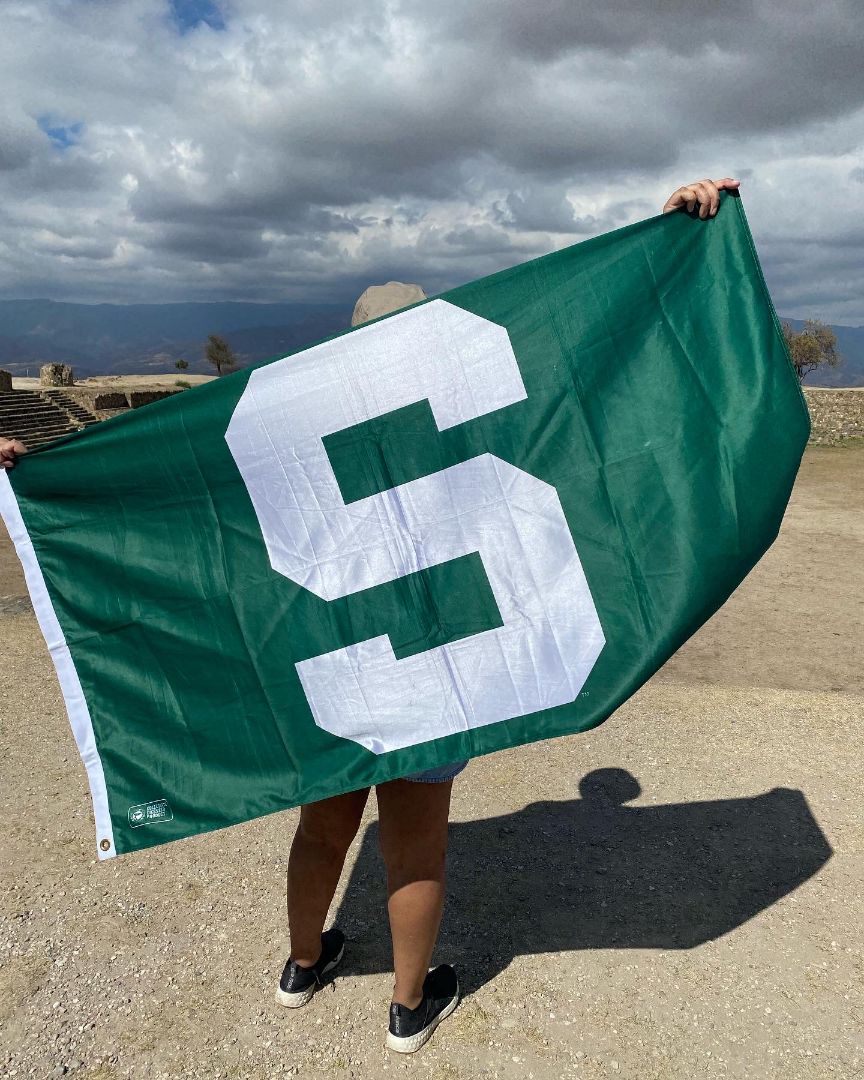 Charlotte holding Spartan flag behind her back at Mayen ruins in Mexico