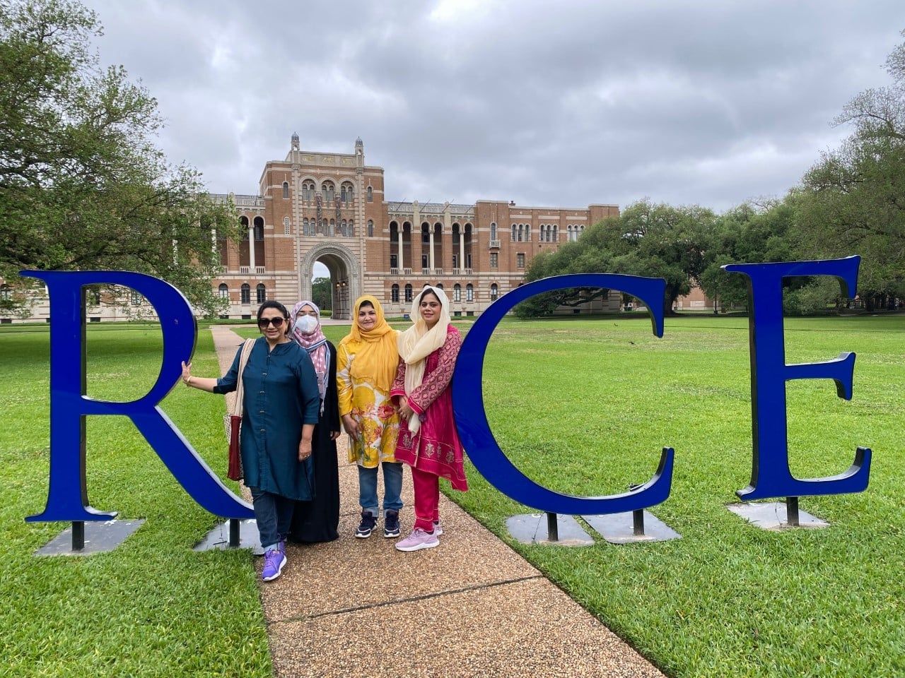 Four scholars stand in front of Rice University sign