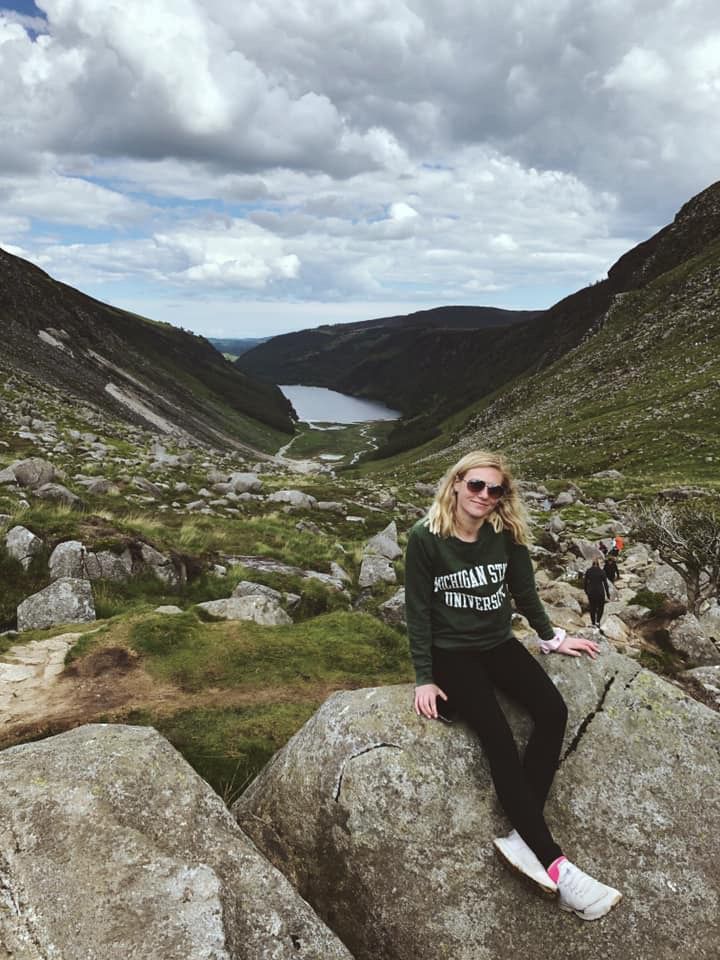 Cecelia sitting on rocks in Ireland countryside