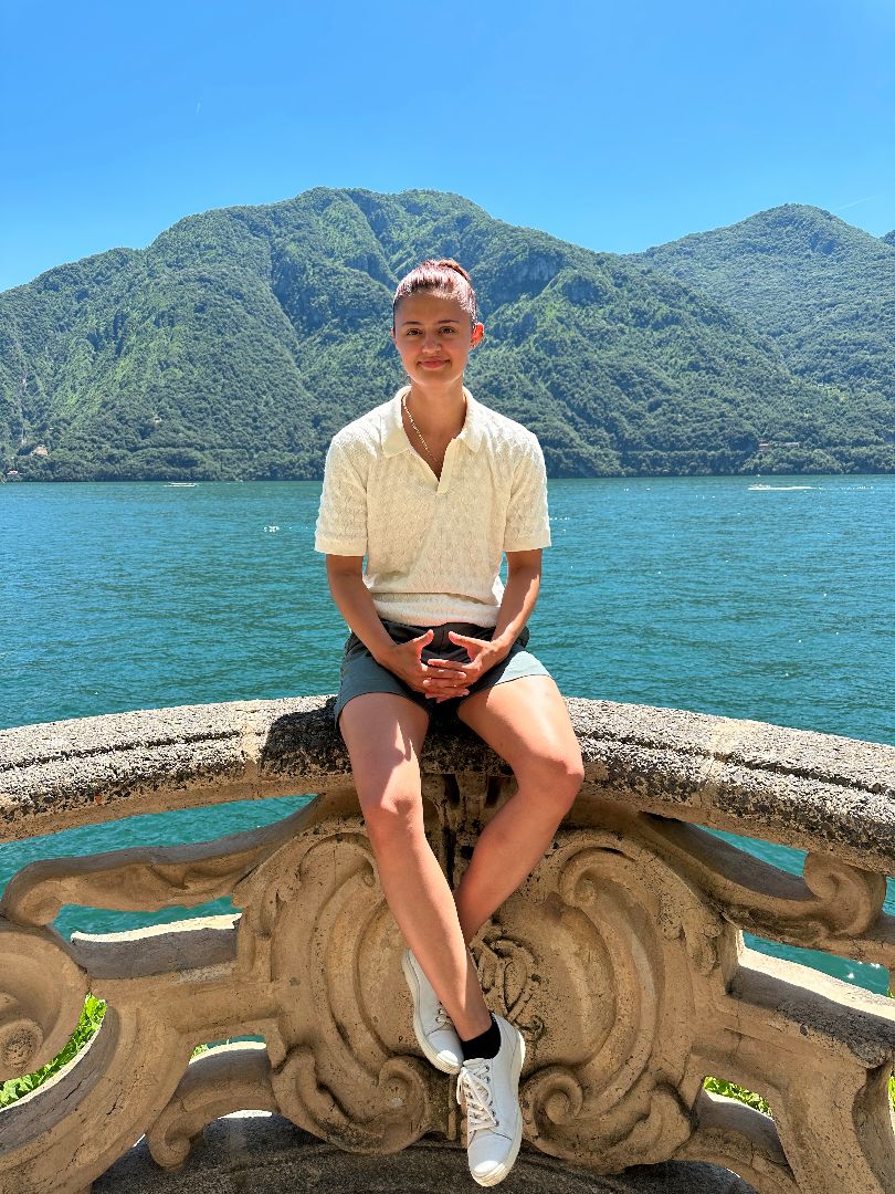 Nicole sitting on ornate concrete railing in front of lake in Italy