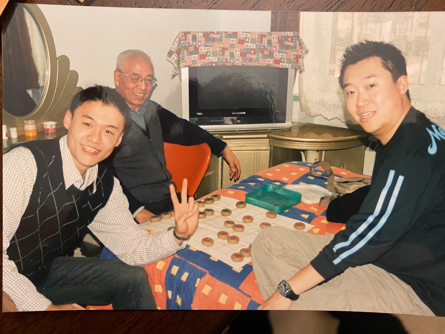 two young men sit with dad around a game board, smiling