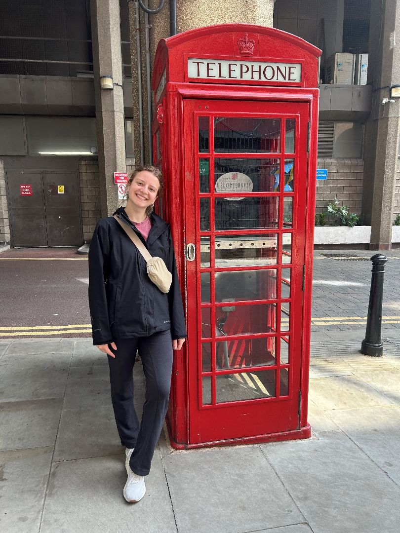 Grace standing by an iconic red telephone booth in London