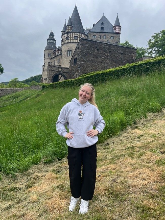 Ava standing on a hill with a castle in the background