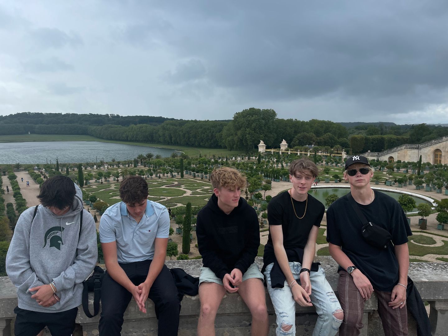 Group of students sitting on a cement wall in front of a garden