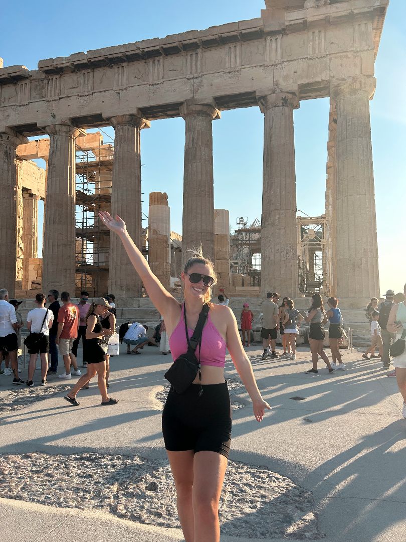 Emma standing in front of the Acropolic with her right arm up