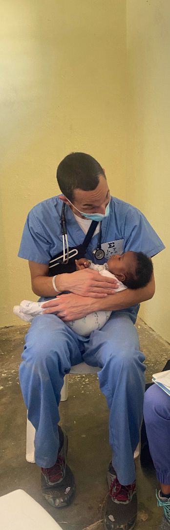 Bruin holding baby at clinic in Dominican Republic