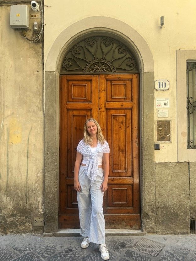 Riley standing in front of a large, arched wooden door in Italy