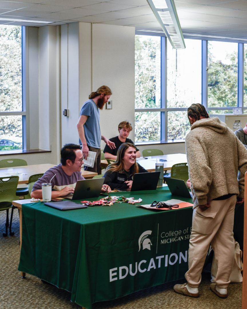 Advisors sit behind a table talking to a student