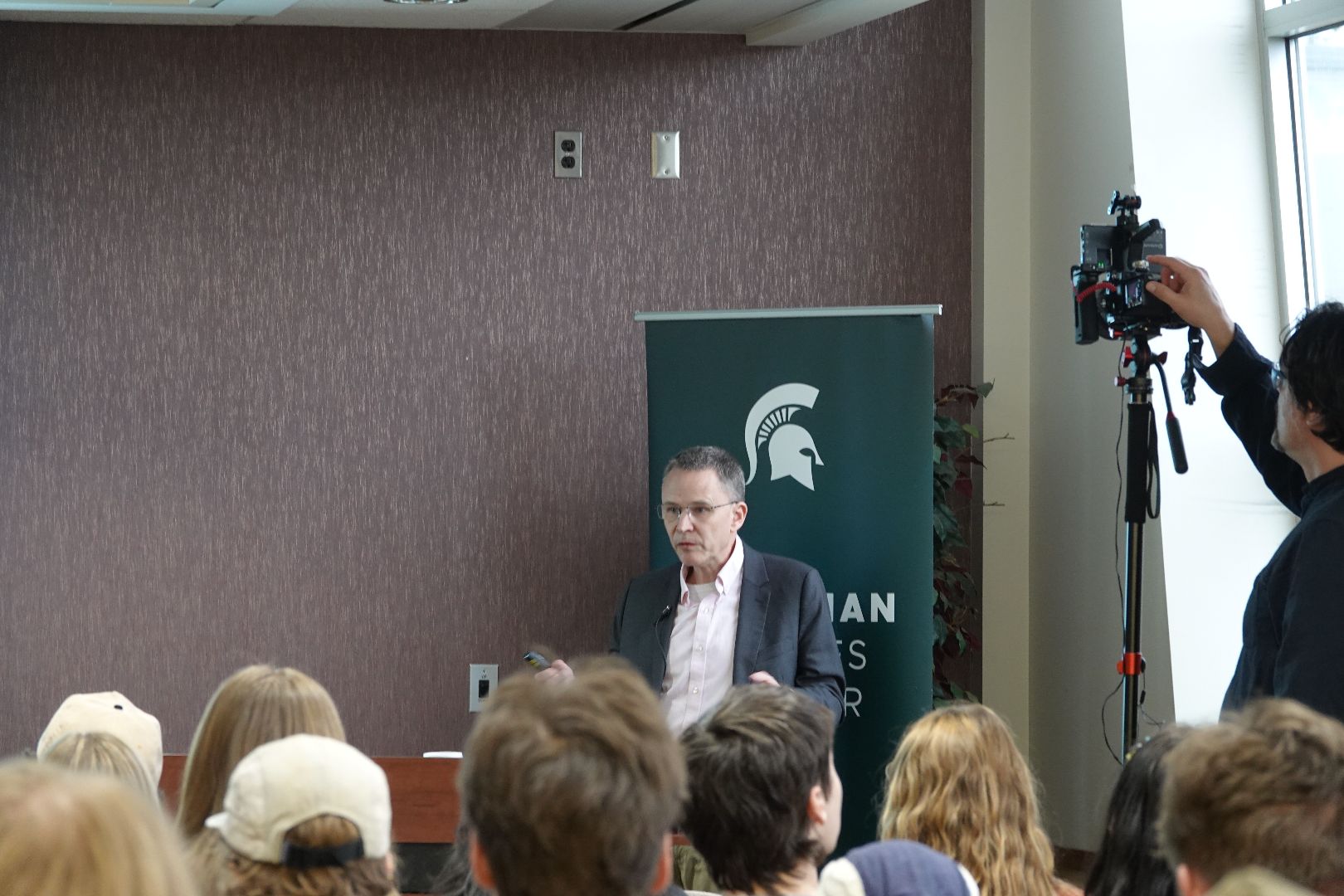 Peter Johnson speaking in front of a Canadian Studies Center banner. Students are seen in the foreground.