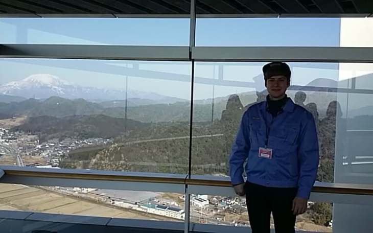 a person standing by a window overlooking buildings around mountains